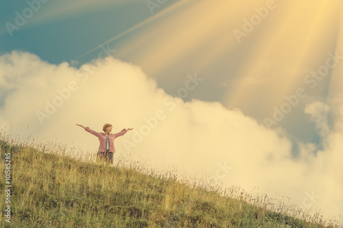 Young girl holds hands up against the sky and hillside