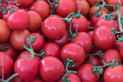 Many red tomatoes at farmers market stall.
