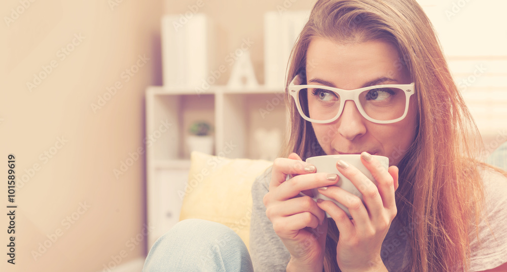 Happy young woman drinking coffee on her couch Happy young woman drinking coffee on her couch