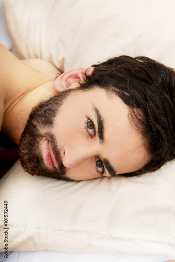 Young muscular man lying in bed.