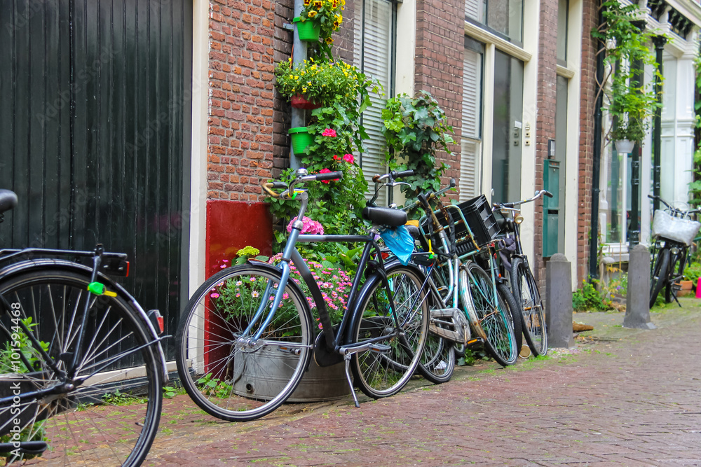 Parked bicycles near the brick house on the narrow street