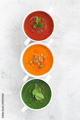 assortment of colorful vegetable cream soup on white background