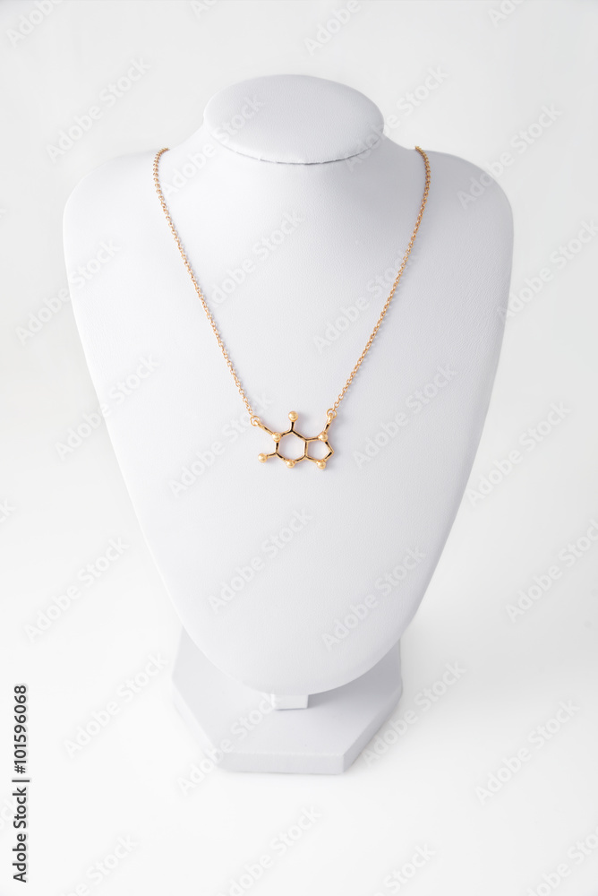 Necklace in shape of caffeine molelule made of gold on white stand. Luxury women accessories. Necklace in shape of caffeine molelule made of gold on white stand. Luxury women accessories.