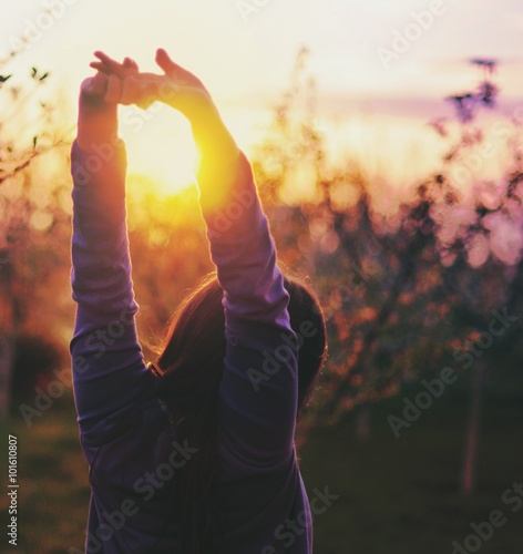 girl in the apple orchard that admires the sunset and relaxes