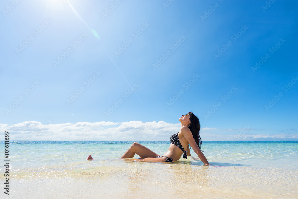 Young happy woman in black bikini enjoys sunny day on beach. Tropical vacation