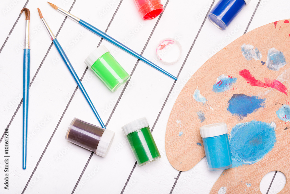 Watercolor and tempera with different paint brushes on a white wooden background Watercolor and tempera with different paint brushes on a white wooden background