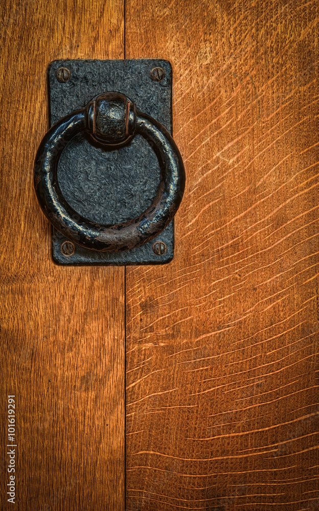 Old black metal circular knocker on oak door Old black metal circular knocker on oak door