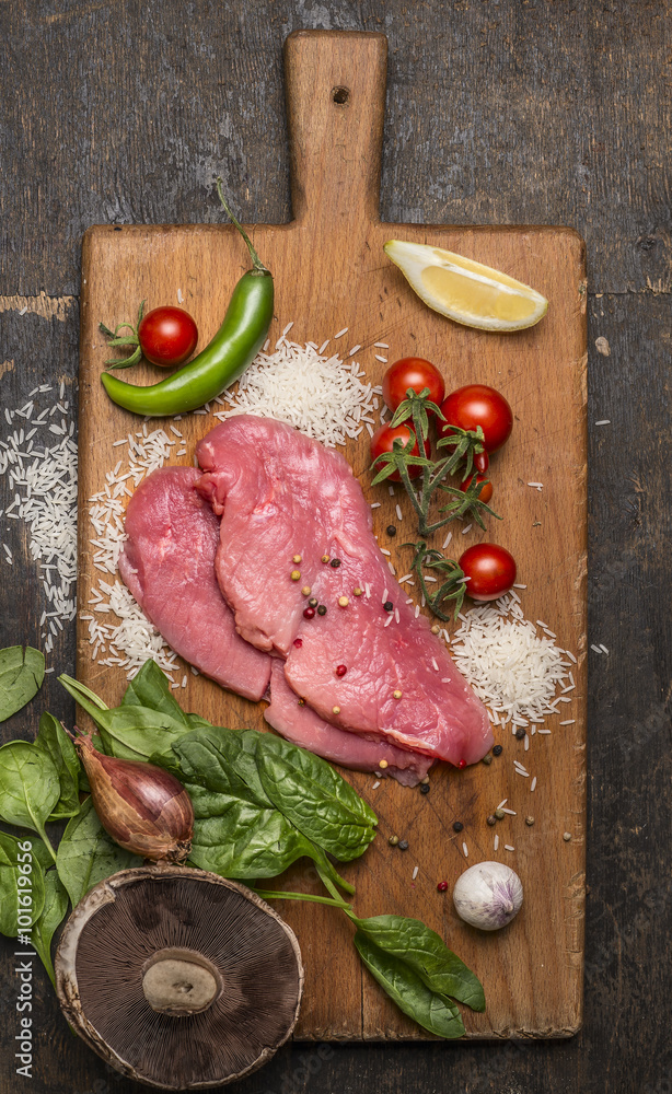 raw pork on a cutting board with hot peppers, herbs and lemon on wooden rustic background top view close up raw pork on a cutting board with hot peppers, herbs and lemon on wooden rustic background top view close up