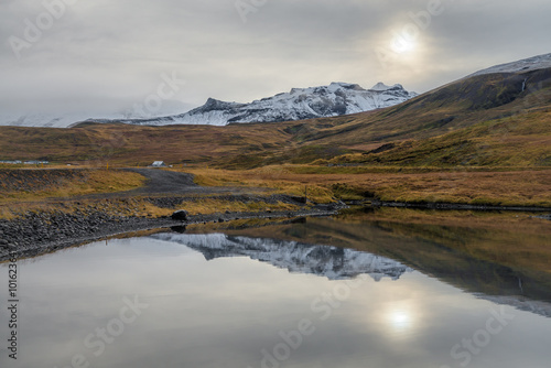 View of snow mountain range reflecting on mirror lake in cloudy day autumn season Iceland