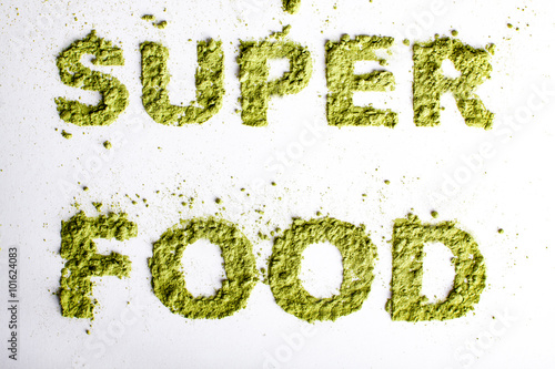 Obraz na płótnie Word superfood piled of .green powder of barley grass on white background. w salonie