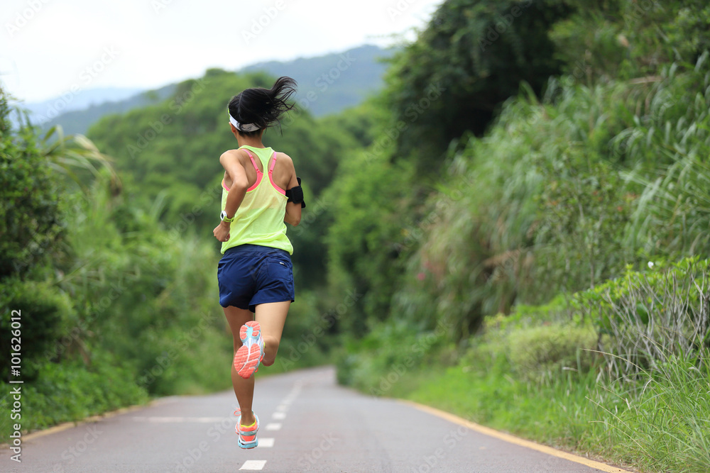 Runner athlete running on forest trail. woman fitness jogging workout wellness concept.