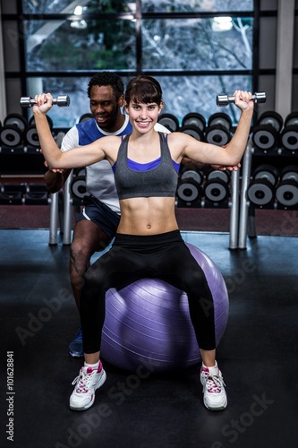 Male trainer helping woman during dumbbells exercise