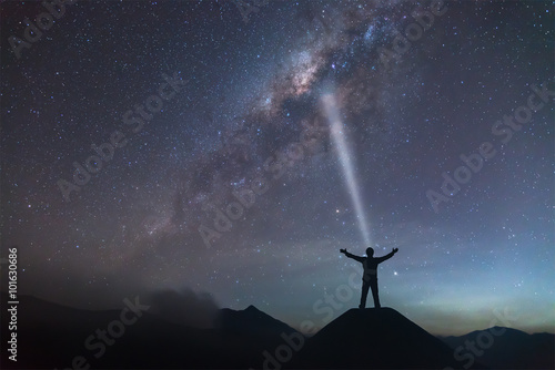 A person is standing next to the Milky Way galaxy spread hand on