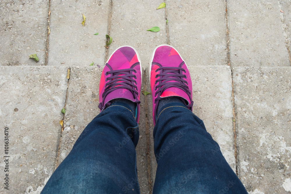 young girl with blue jeans and sweet pink shoes standing on cement floor young girl with blue jeans and sweet pink shoes standing on cement floor