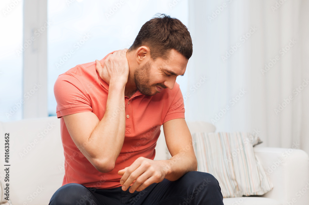 unhappy man suffering from neck pain at home