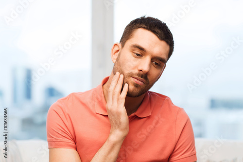 unhappy man suffering toothache at home