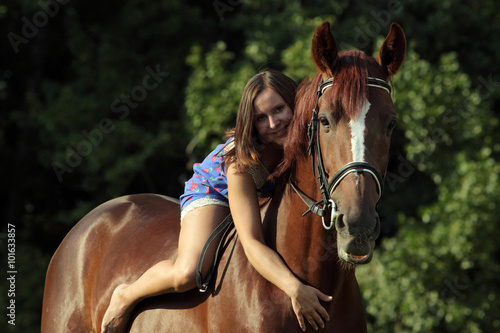 Young woman sit on horse in a evening woods