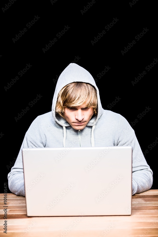 Man in hood jacket hacking a laptop Man in hood jacket hacking a laptop