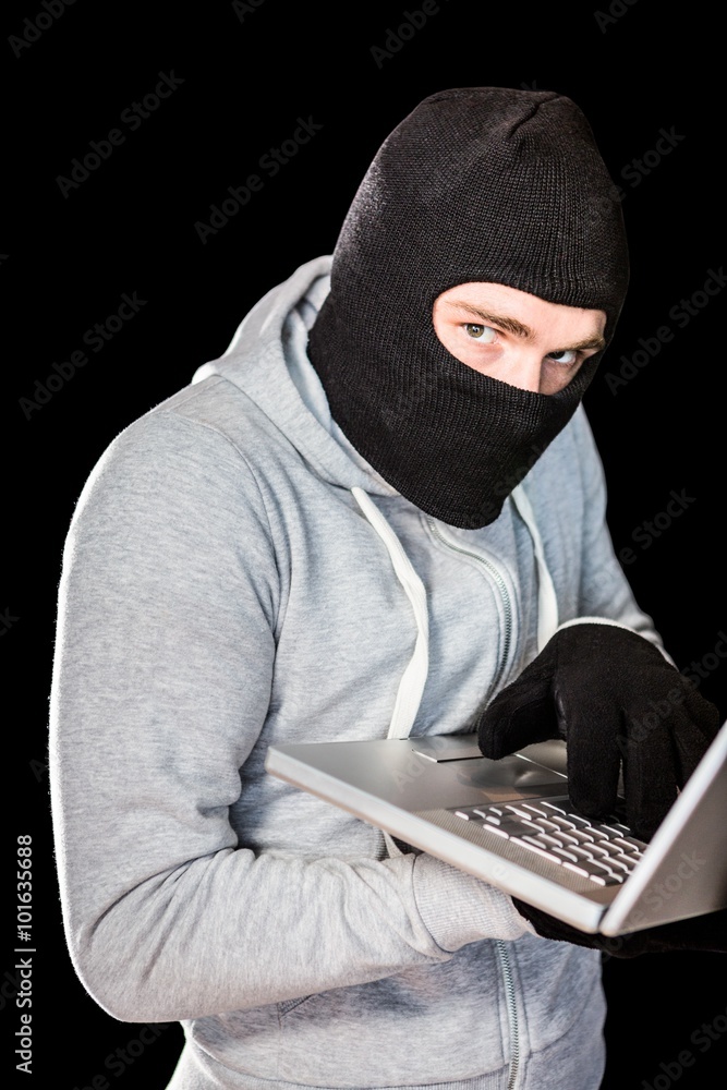 Focused thief with hood typing on laptop Focused thief with hood typing on laptop