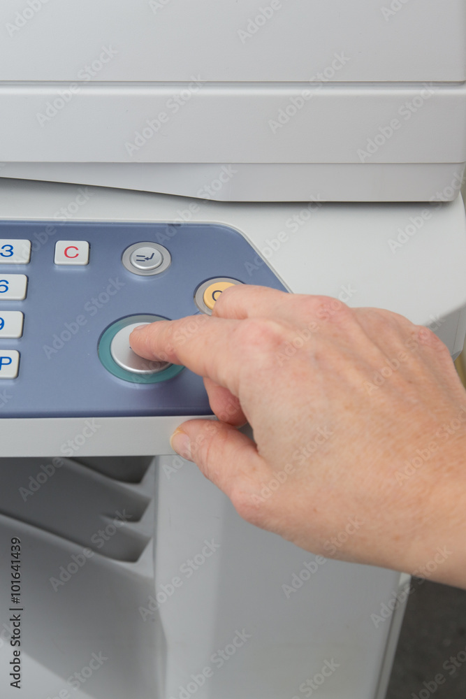 Woman holding finger on start button of laser printer Woman holding finger on start button of laser printer