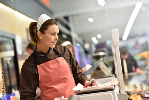 Quadro em tela Woman pork butcher serving sausages to customer