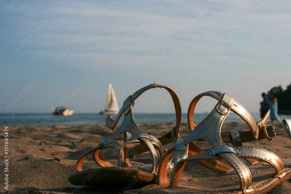 Golden sandals at the beach in evening Golden sandals at the beach in evening