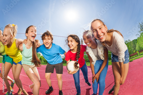 Happy teens standing on the volleyball game court