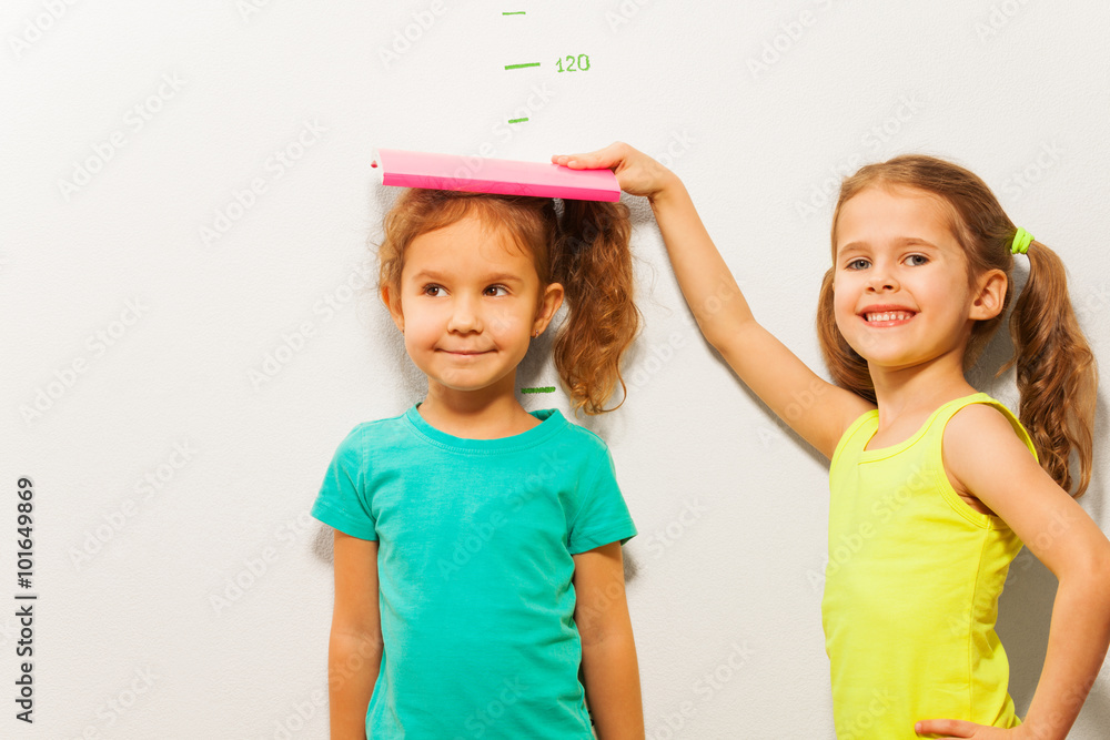 © Sergey Novikov - Girls measure height on wall scale © Sergey Novikov - Girls measure height on wall scale