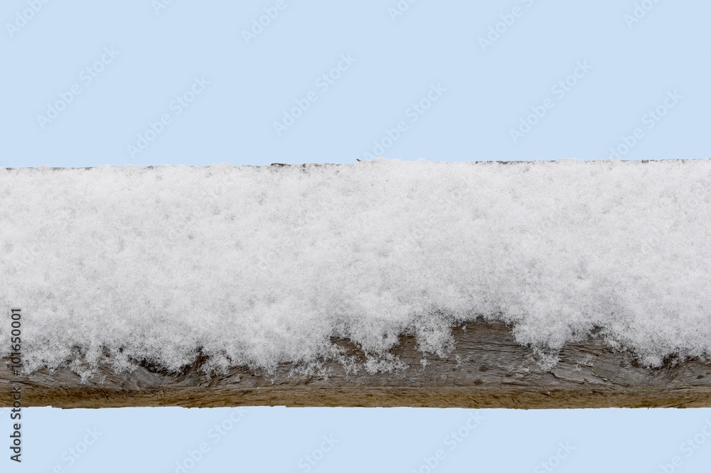 Snow covered old wood fence railing with blue 'sky' background.  