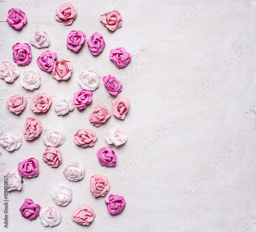 paper roses of different colors stacked on a white wooden background, valentines day
