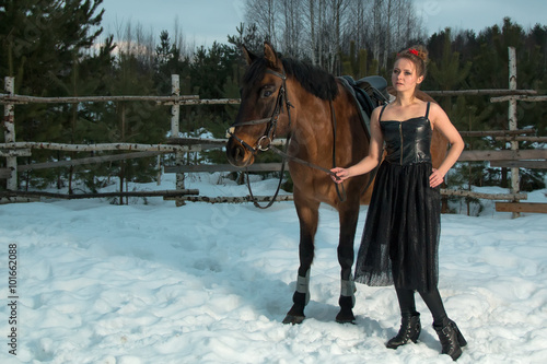 woman posing with a horse in the winter forest