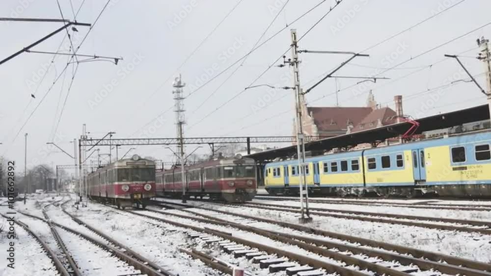 Blue And Yellow Train is Leaving Empty Platform Shelter Two Red Trains Are Stopped Electric Train at The Railway Station Snow on a Ground Winter Snow Blue And Yellow Train is Leaving Empty Platform Shelter Two Red Trains Are Stopped Electric Train at The Railway Station Snow on a Ground Winter Snow