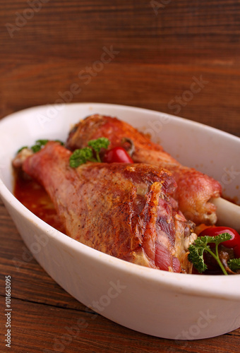 Baked turkey legs in white plate on dark background