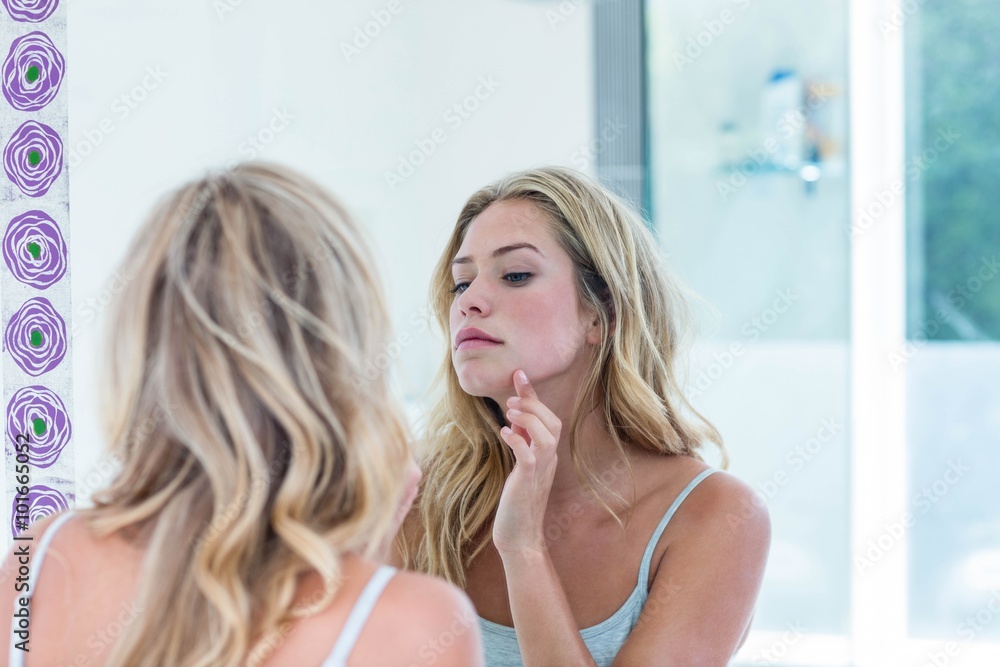 Focused beautiful woman looking at herself in the bathroom Focused beautiful woman looking at herself in the bathroom