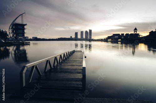 beautiful morning at lakeside. building reflection on the lake surface  soft and dramatic cloud with colorful on the sky. wooden jetty and soft look on the lake surface.