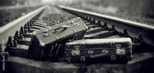 The black-and-white image of suitcases on railway rails.
