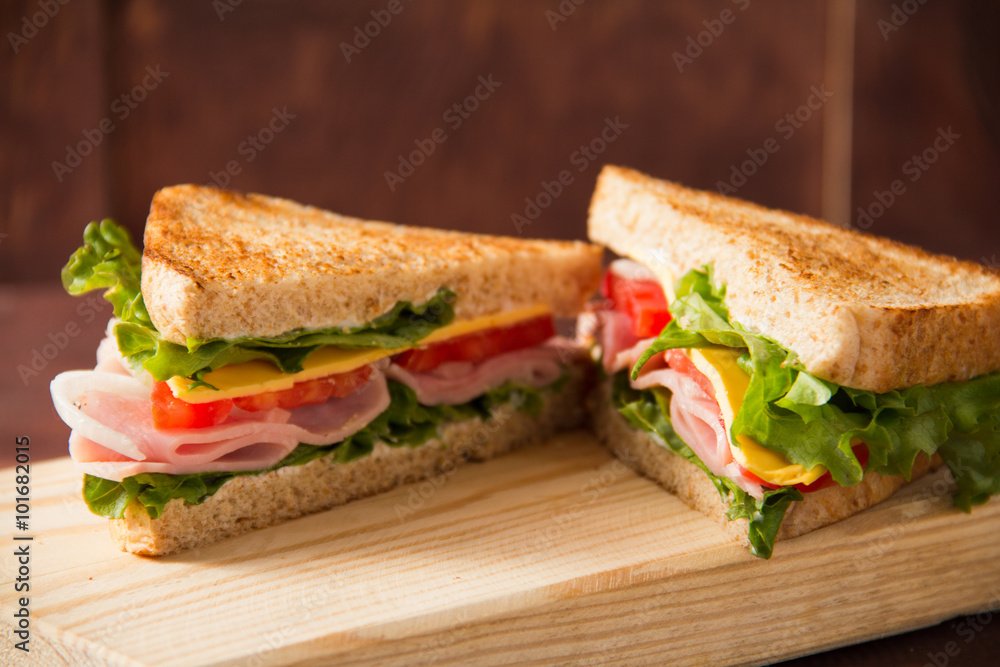 Sandwich tomato, lettuce, onion and yellow cheese on a wooden table Sandwich tomato, lettuce, onion and yellow cheese on a wooden table