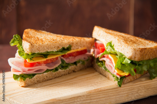 Sandwich tomato, lettuce, onion and yellow cheese on a wooden table
