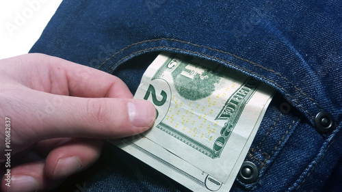 Hand pulls money out of pocket jeans photo