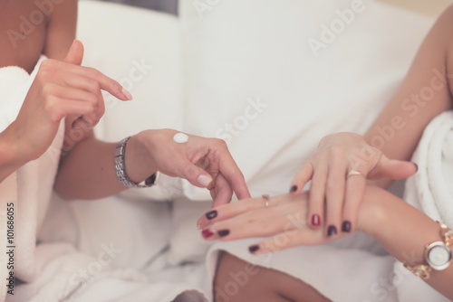 Two woman applying cosmetic hand cream home spa.
