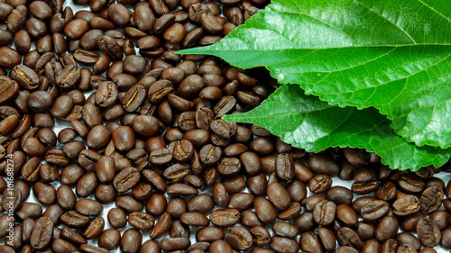 Roasted coffee beans with green leaf.