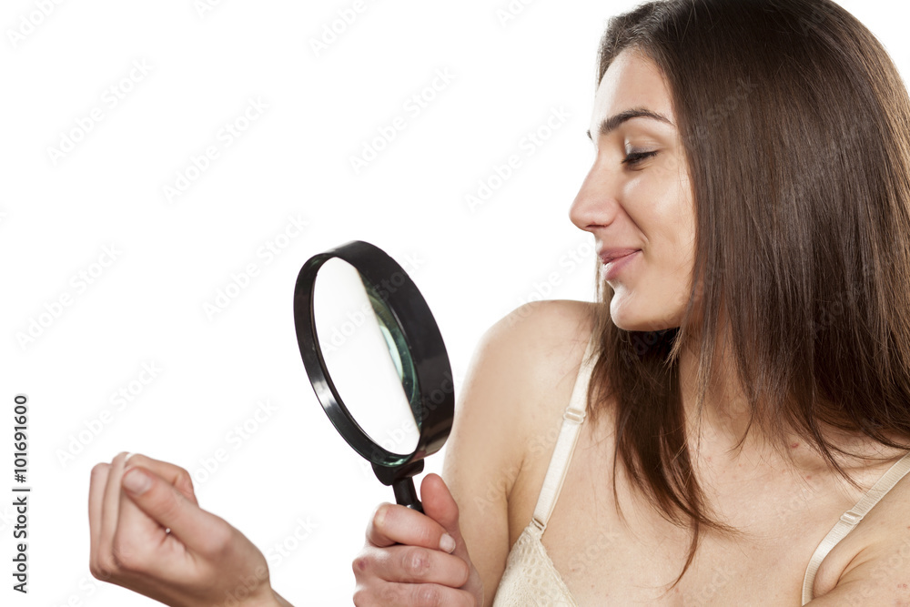 satisfied young woman looking at her nails through a magnifying glass satisfied young woman looking at her nails through a magnifying glass