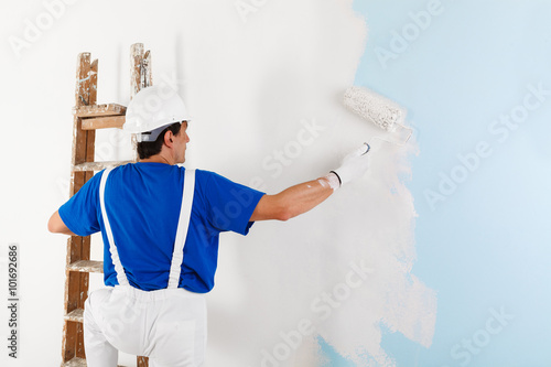 painter painting a wall with paint roller photo