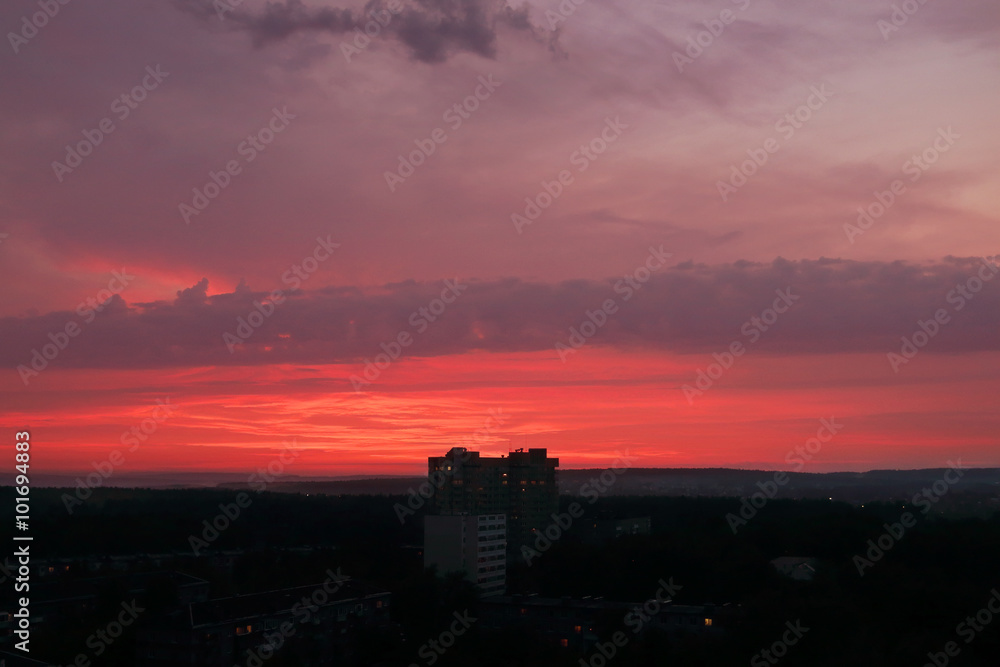 Beautiful summer red sunset and silhouettes of buildings and sky