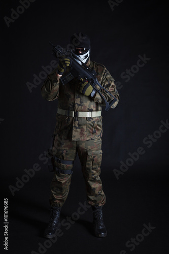 Anti terrorist dressed in camouflage, holding a gun, looking at camera