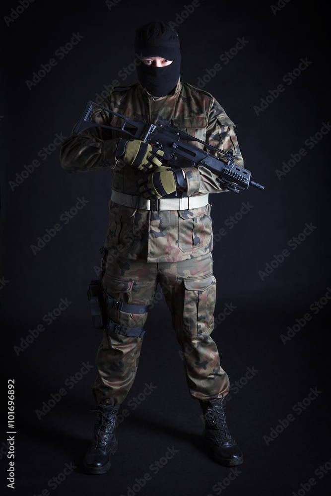 Anti terrorist dressed in camouflage, standing with a gun, looking at camera Anti terrorist dressed in camouflage, standing with a gun, looking at camera