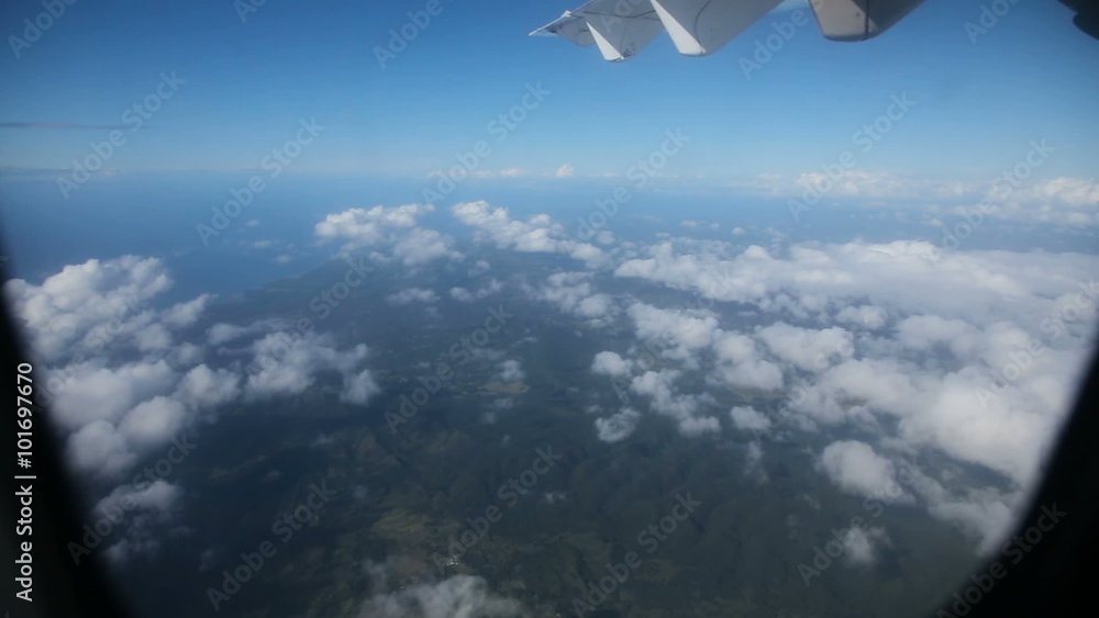View from the airplane window on a tropical island.Clouds and sky as seen through window of an aircraft.Tropical jungle.Wing aircraft View from the airplane window on a tropical island.Clouds and sky as seen through window of an aircraft.Tropical jungle.Wing aircraft