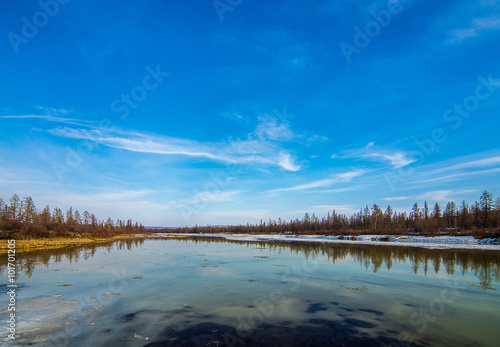 Spring landscape with forest, river and clouds on the blue sky 