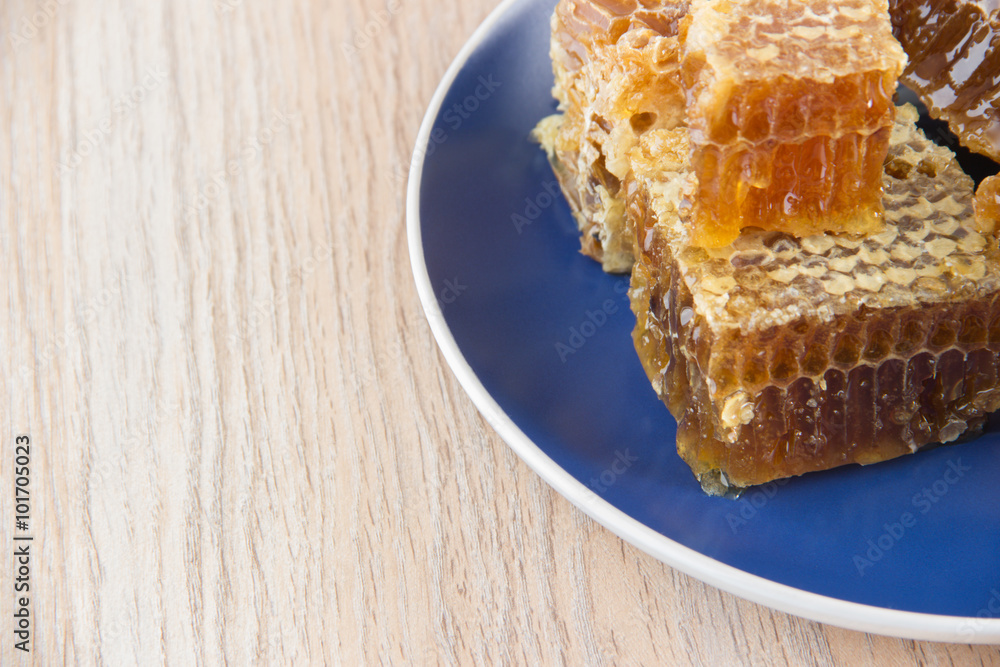 Pieces of golden honey comb on a table with tea, lemon and cinna Pieces of golden honey comb on a table with tea, lemon and cinna