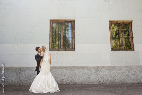 Bride looks at the camera. Groom stands back photo